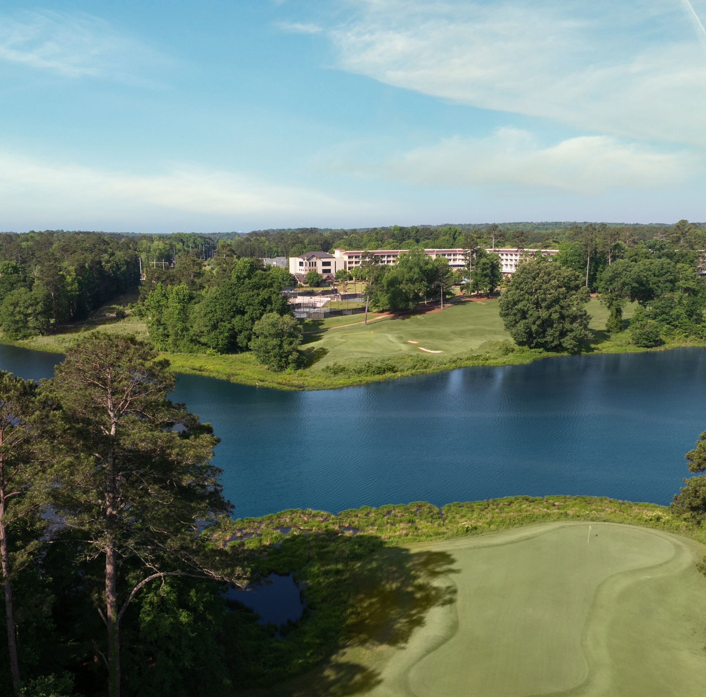 Golf course green with lake and forest