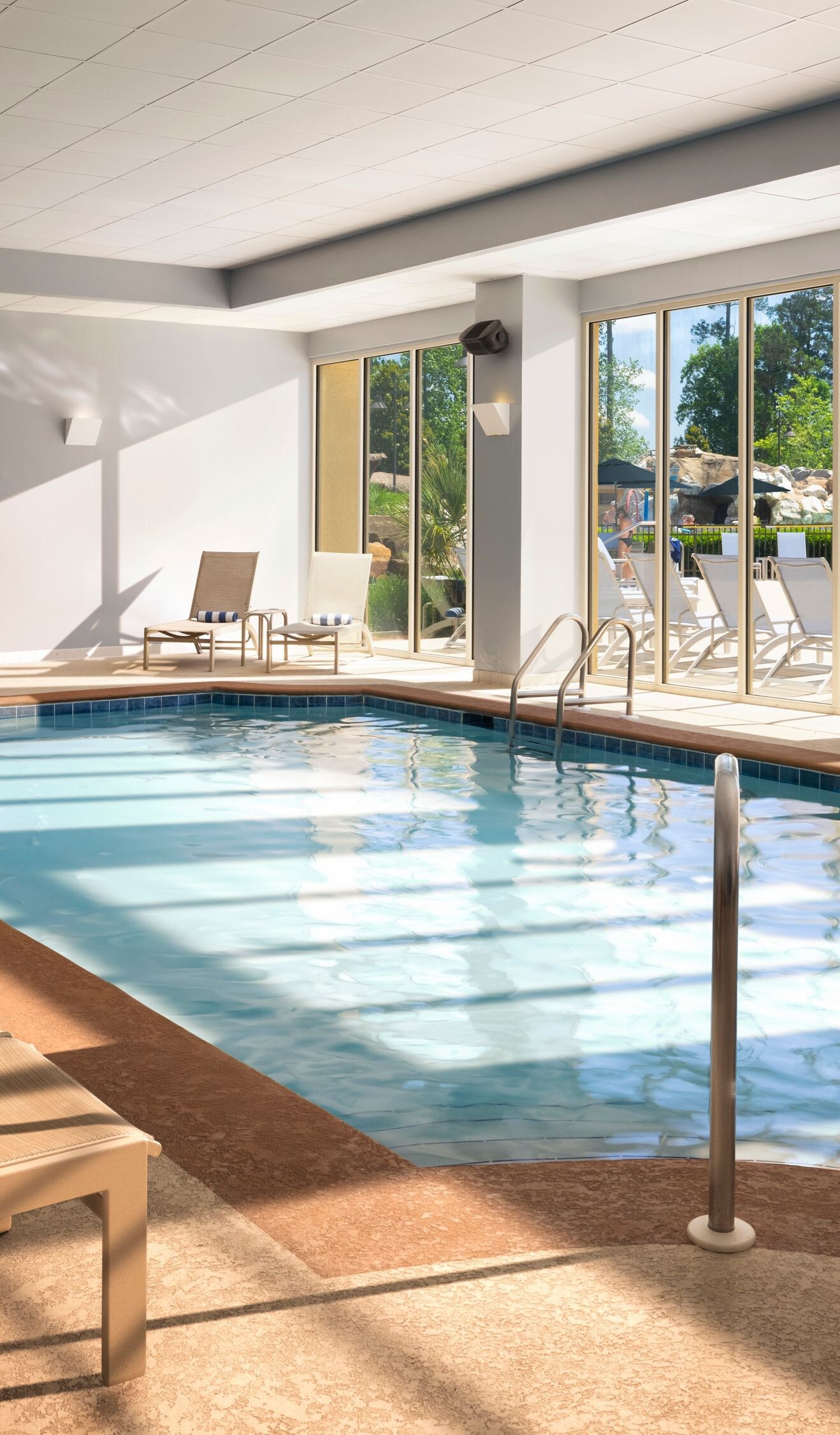 Indoor pool with lounge chairs and hot tub