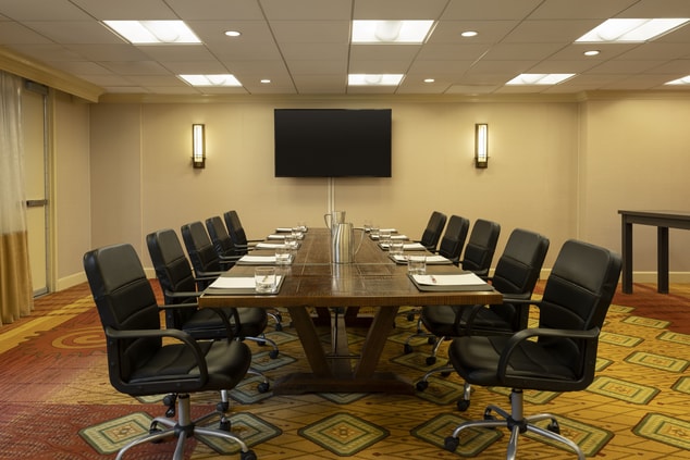 Boardroom with black chairs, long table, and TV