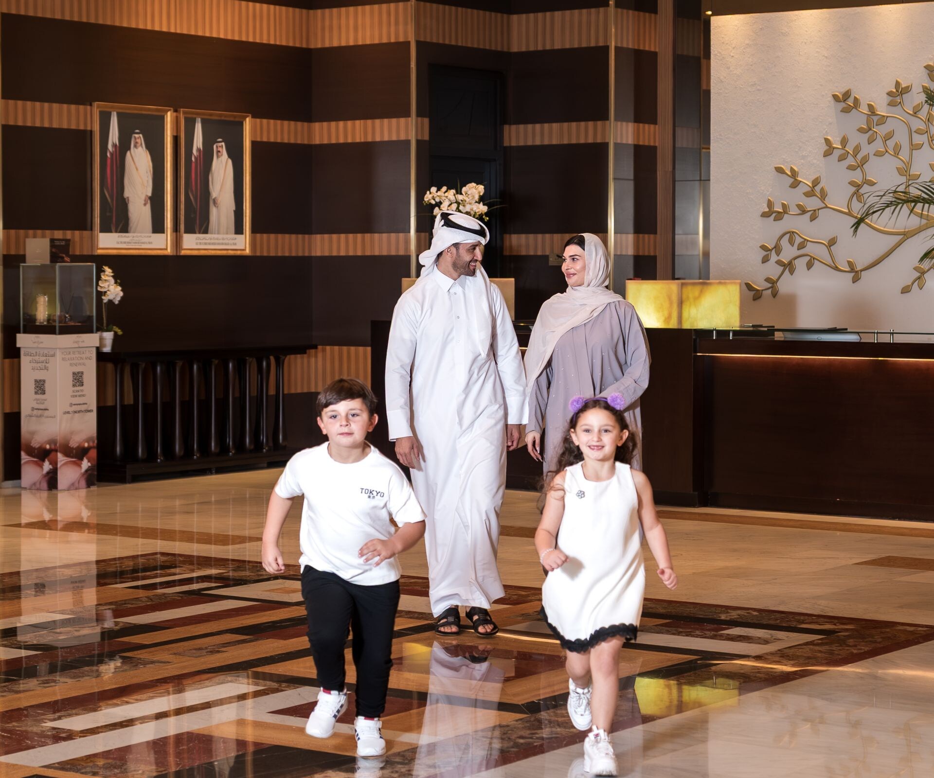 Smiling Arabic family walking through hotel lobby