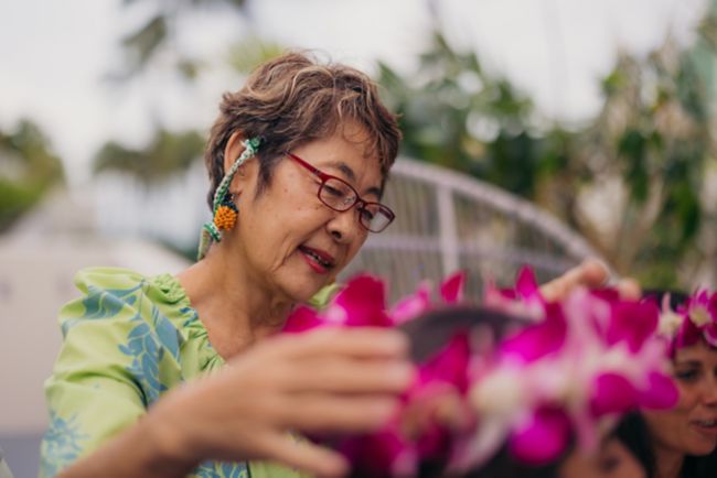Women helps place haku flower lei on guest