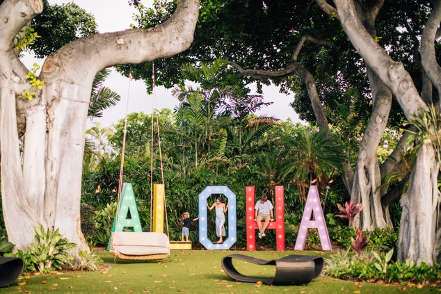 Family on a large sign that says ALOHA.