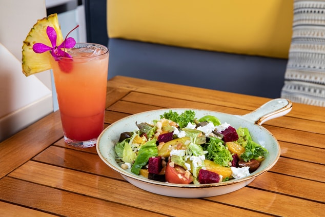 A salad and cocktail with pineapple garnish. 