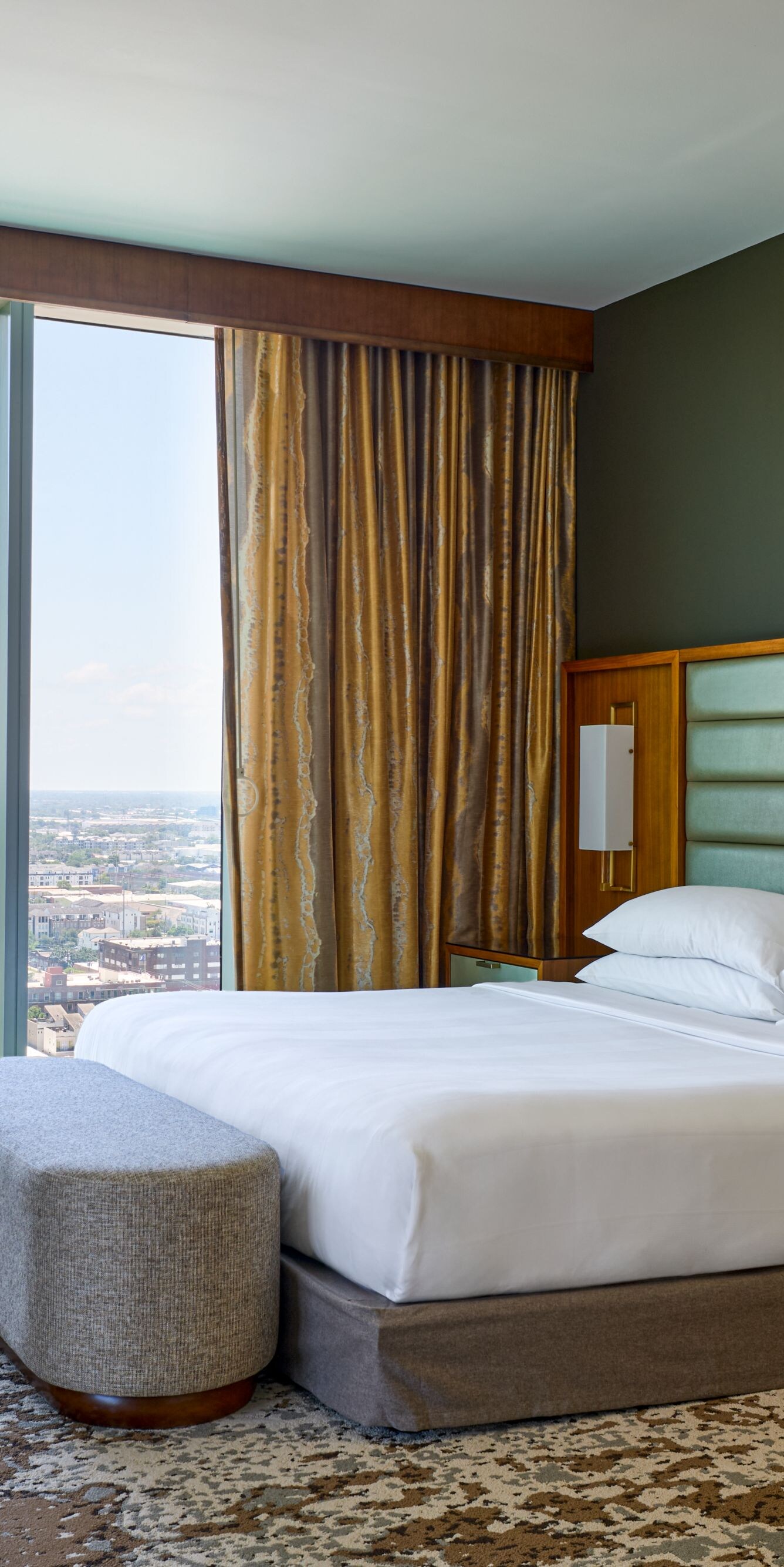 Cama tamaño King con banco y silla con vista a la ciudad