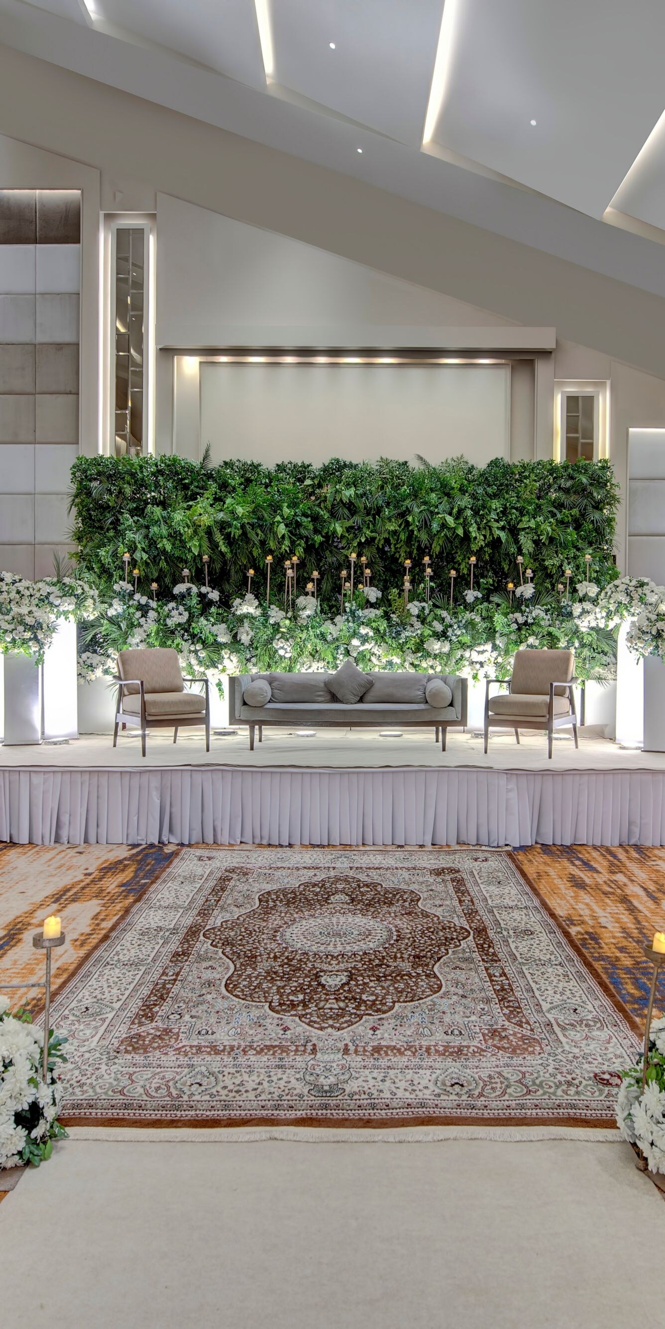 Ballroom stage with sofa, greenery, aisle candles