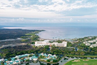 Aerial view of shops, hotel, golf, and ocean.