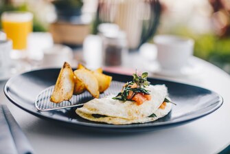 An Egg white omelet, home fries, on black plate.