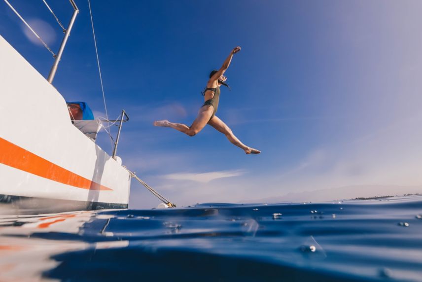 Woman jumping off boat into the ocean
