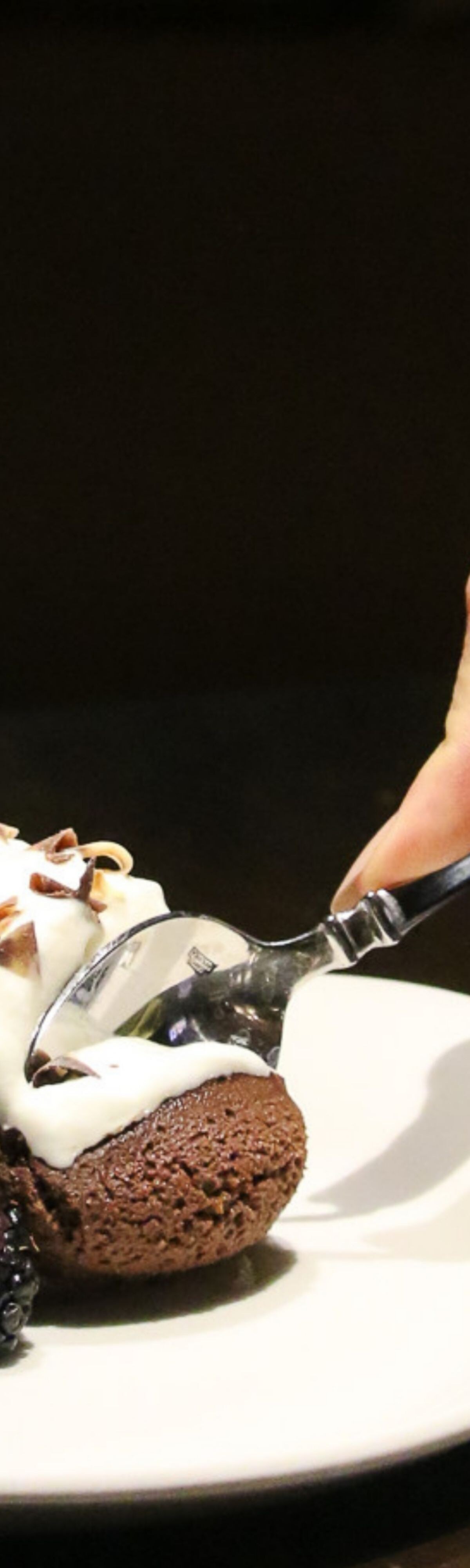 Person putting spoon into chocolate dessert