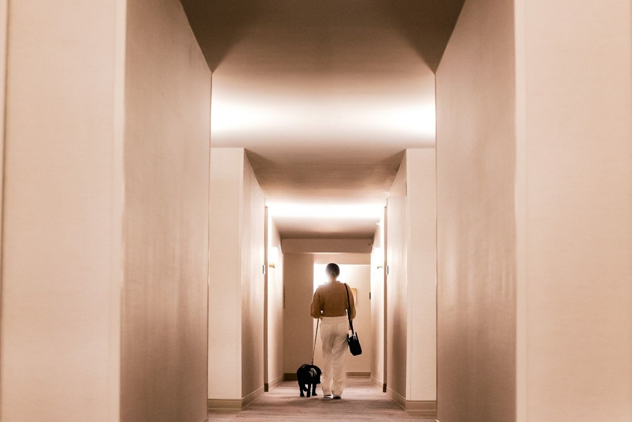 Girl walking down hotel hallway with black dog