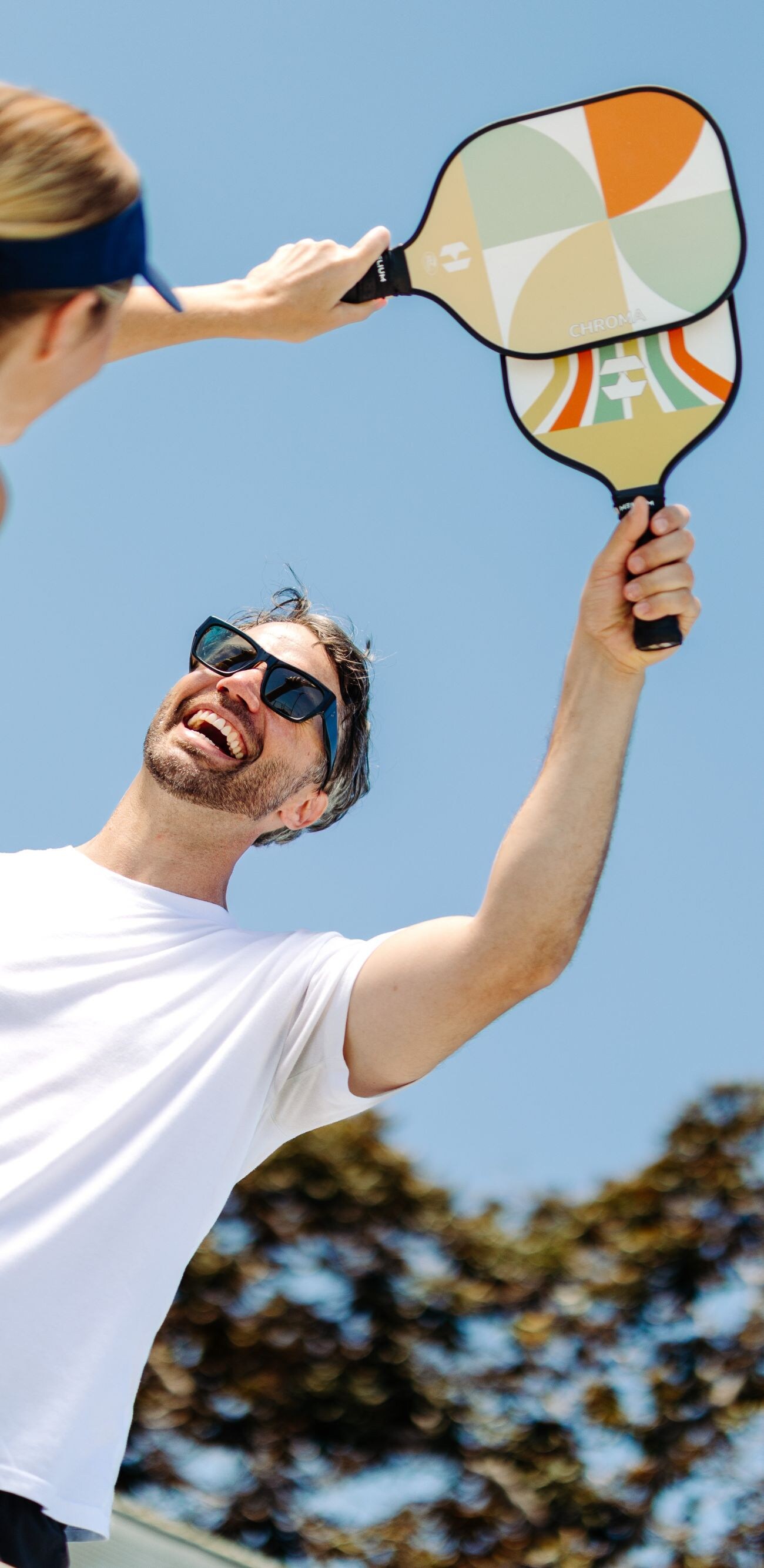 Man and woman holding up pickleball paddles