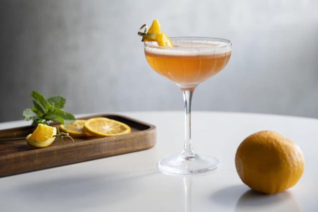 Cocktail garnished with orange, orange on table