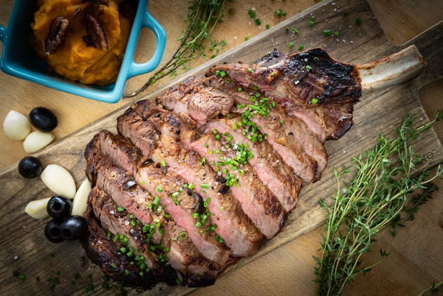 Steak on a cutting board with green onion garnish.