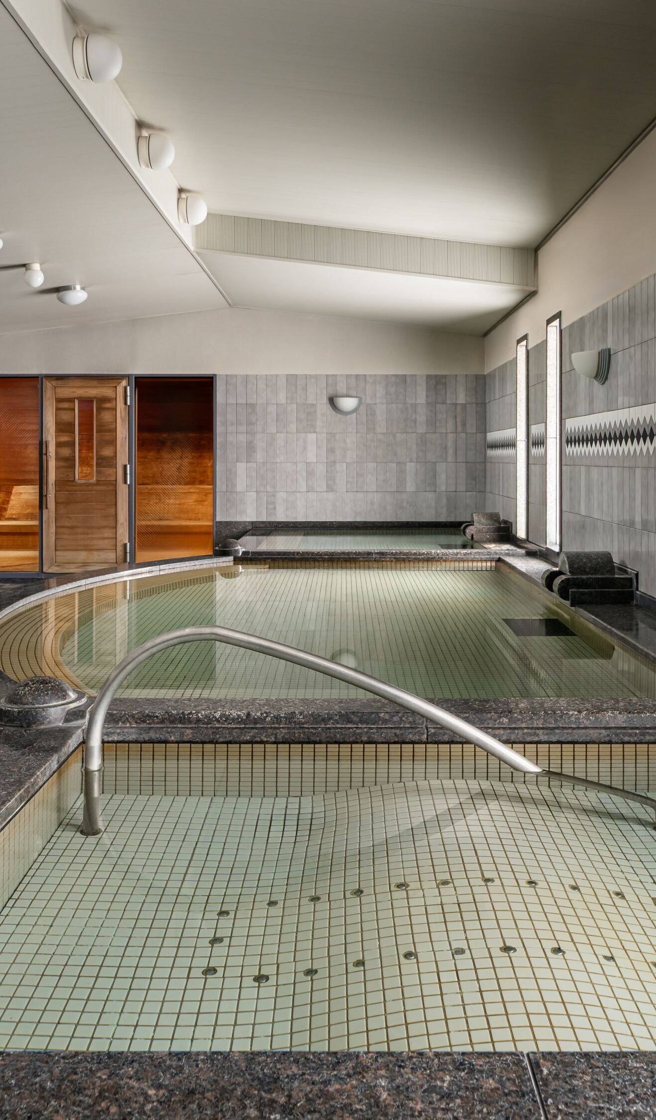 Indoor spa pool with steps and tiled walls