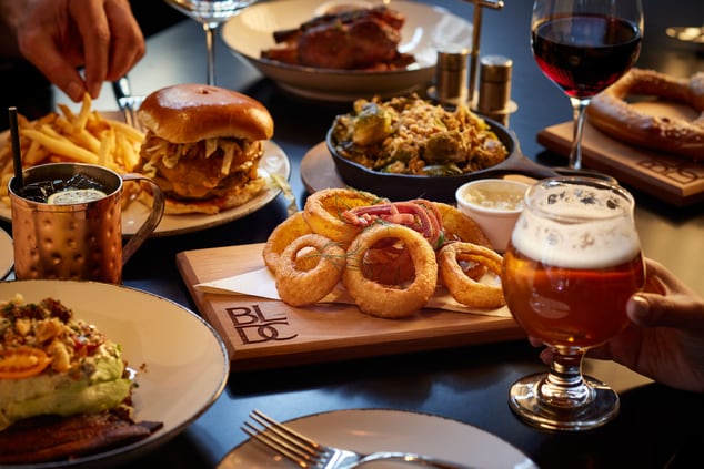 a table with a burger, onion rings and beer