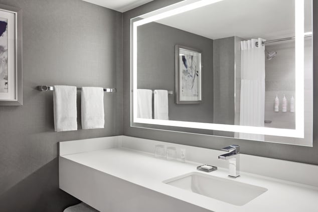 Bathroom counter with mirror, lights, towels, tub