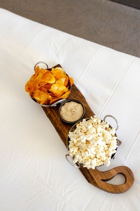 a board of chips, popcorn, and dip