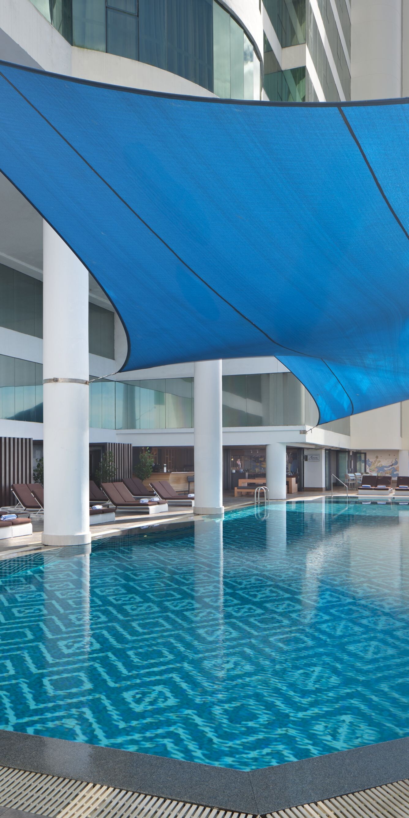 Outdoor pool with blue shade and loungers