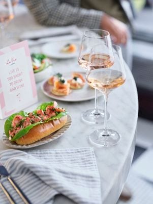 Two Wine Glasses on a table with a lobster roll