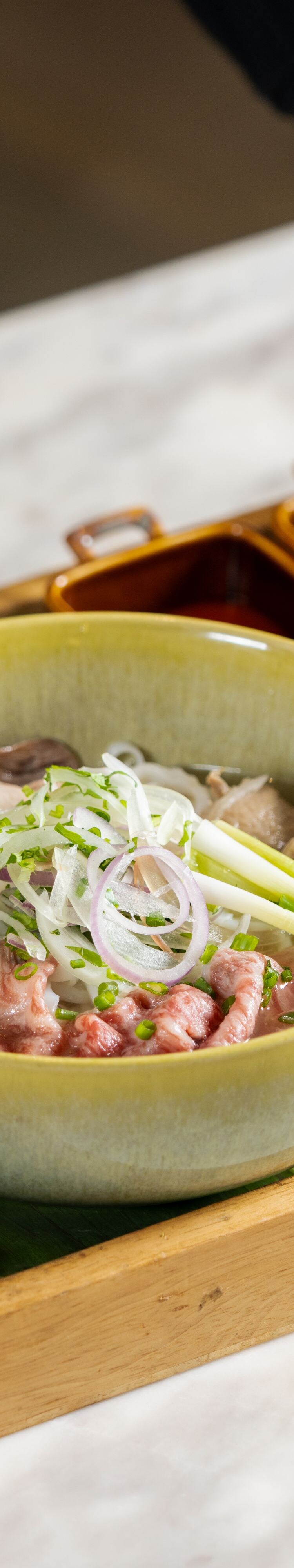 Bowl of noodle soup on wooden serving tray