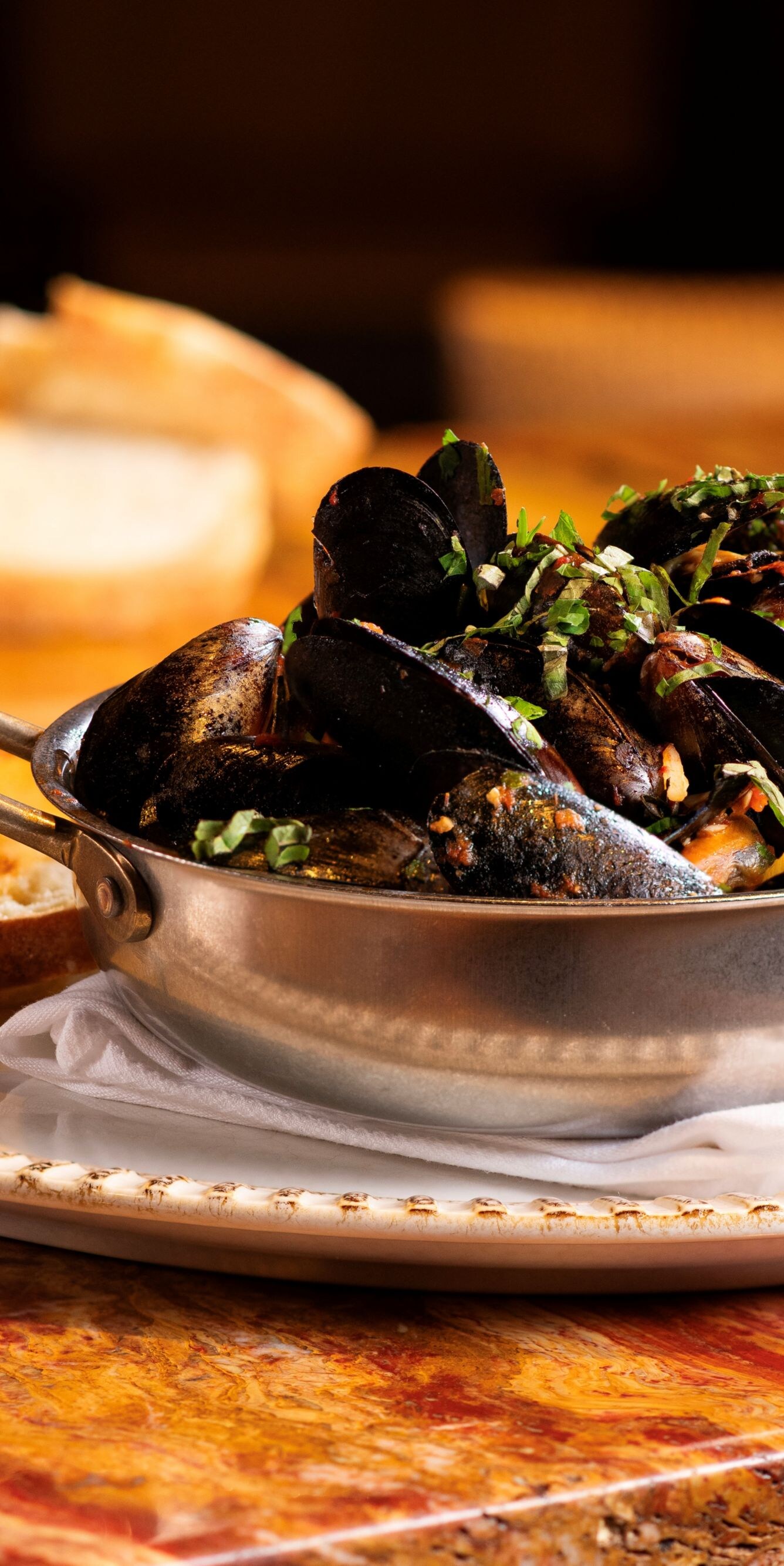 Glass of wine, braised mussels in silver bowl.