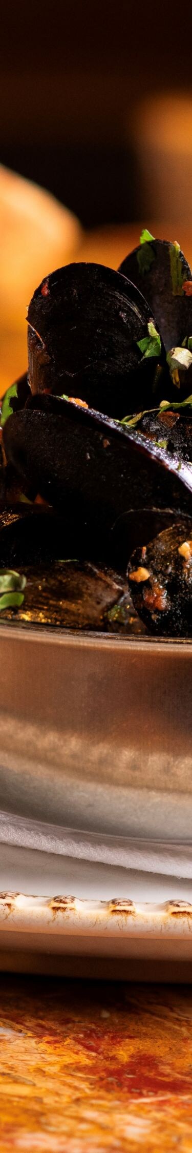 Glass of wine, braised mussels in silver bowl.
