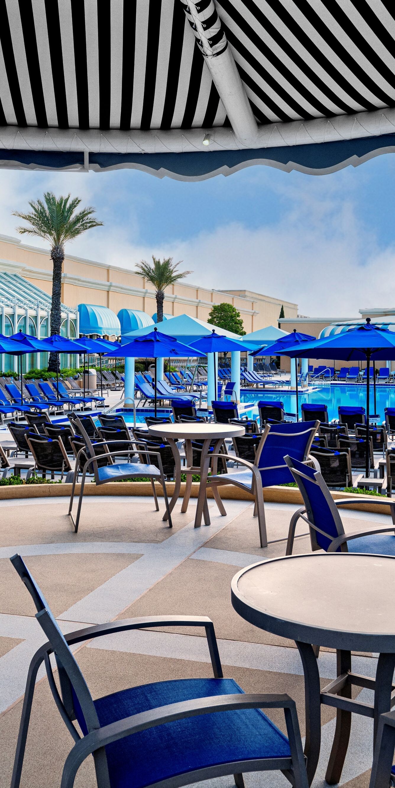 Tables, chairs under awning, lounge chairs.