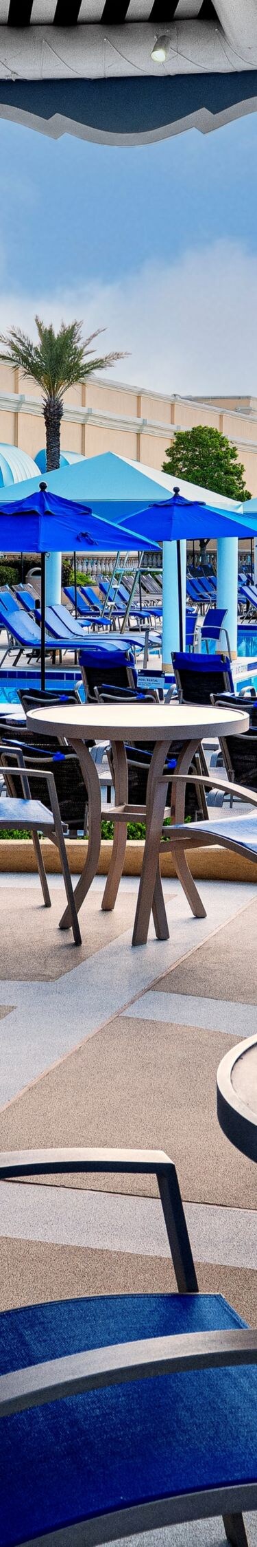Tables, chairs under awning, lounge chairs.