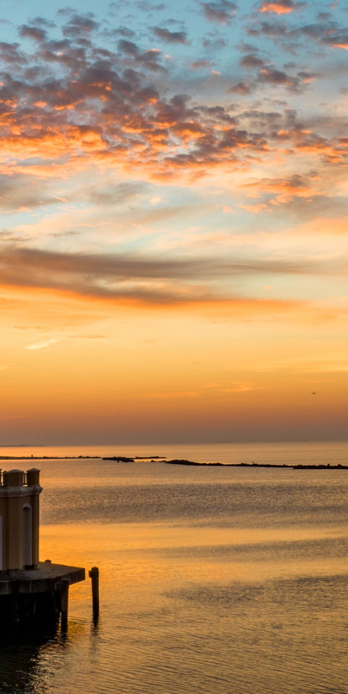 Lighthouse overlooking water, boat, dusk.
