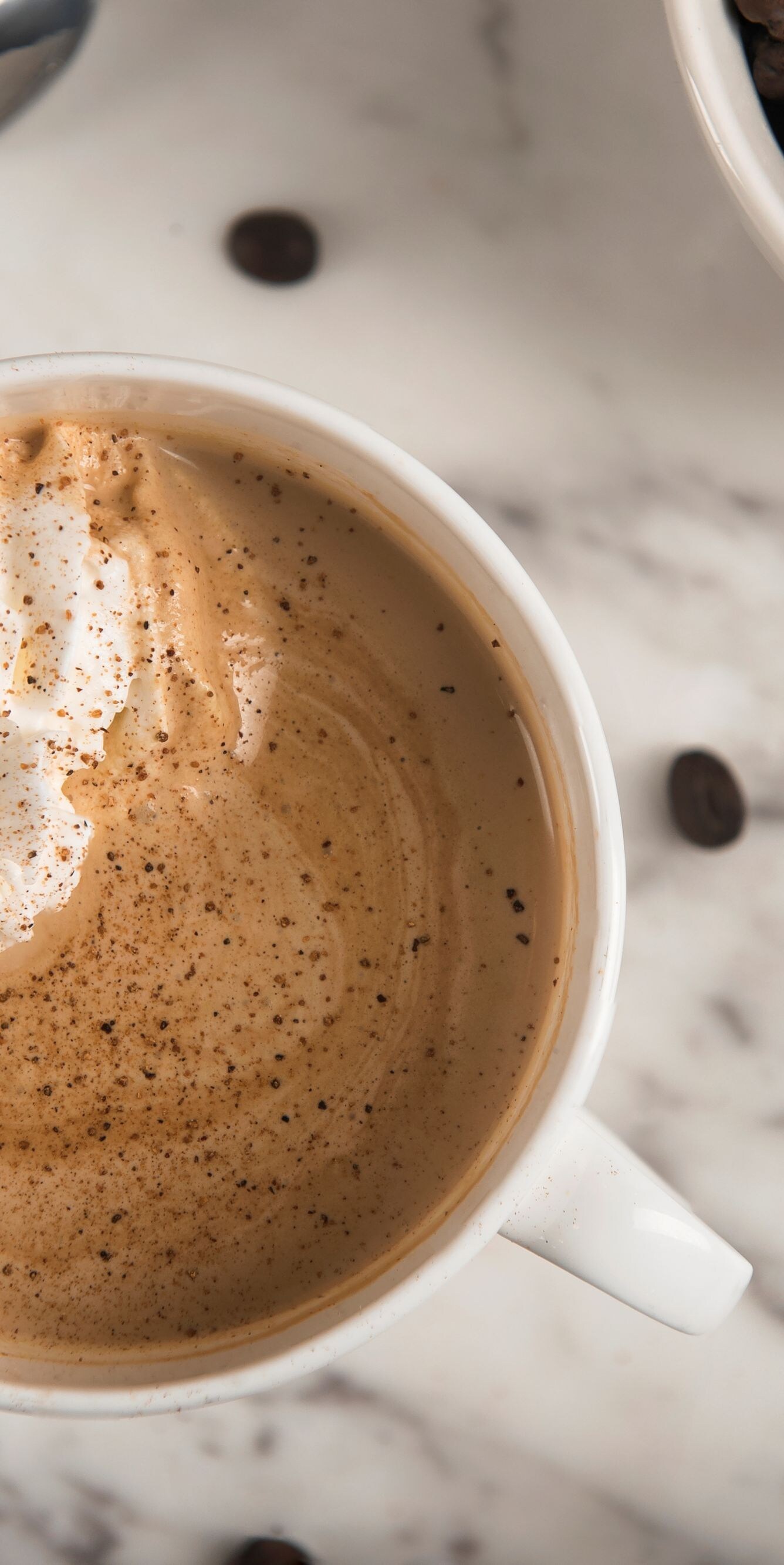 Mug filled with coffee, whipped cream, coffee bean