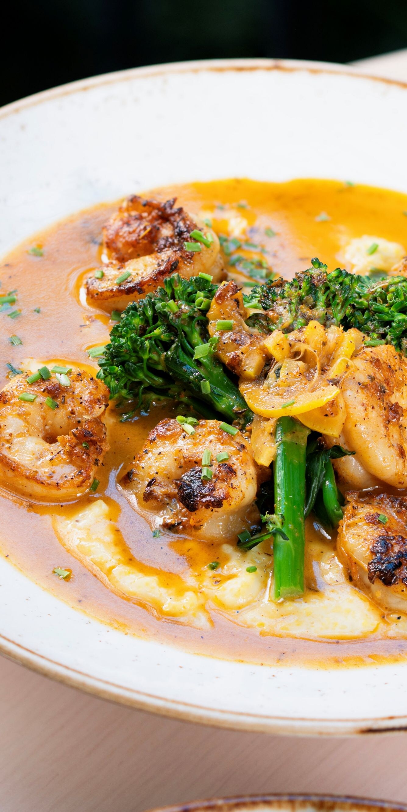 Shrimp, broccolini, grits in a white bowl.