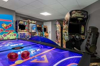 Sala de juegos con mesa de hockey y juegos arcade