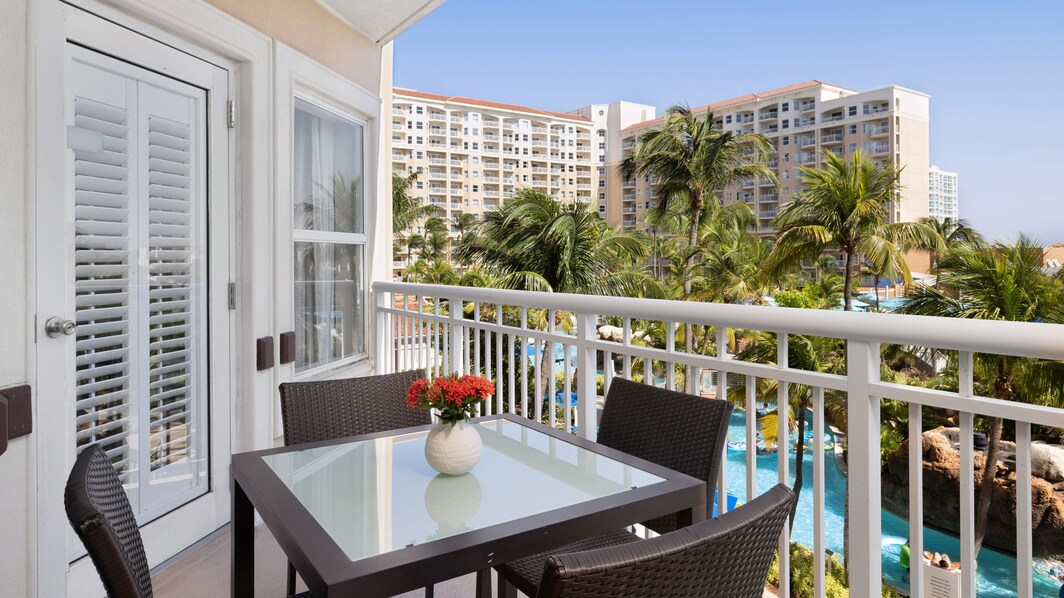 Furnished balcony overlooking pool, palm trees 