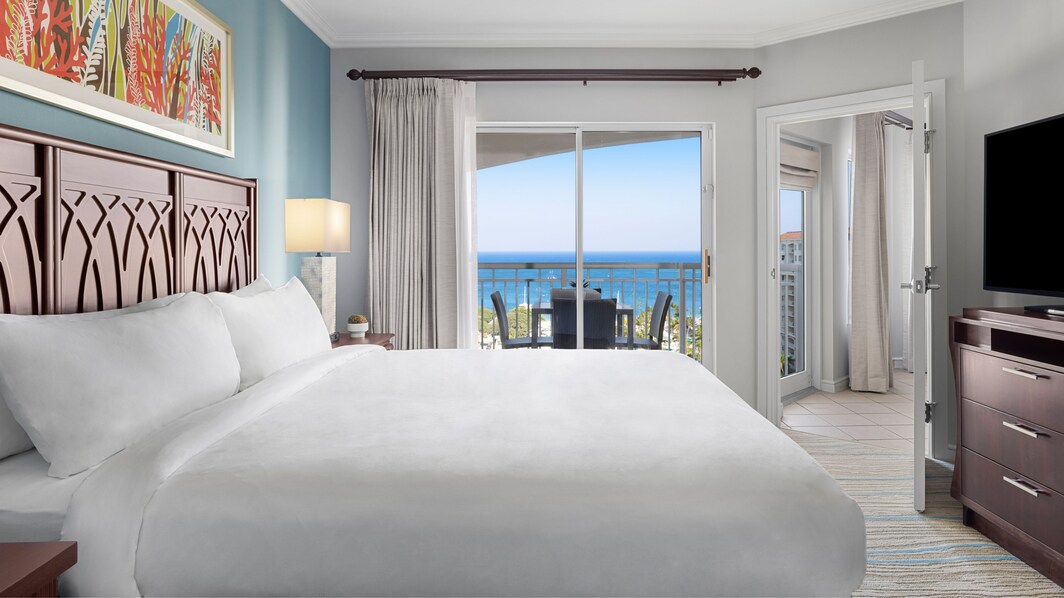 King bed, TV, balcony looking ocean and grounds  