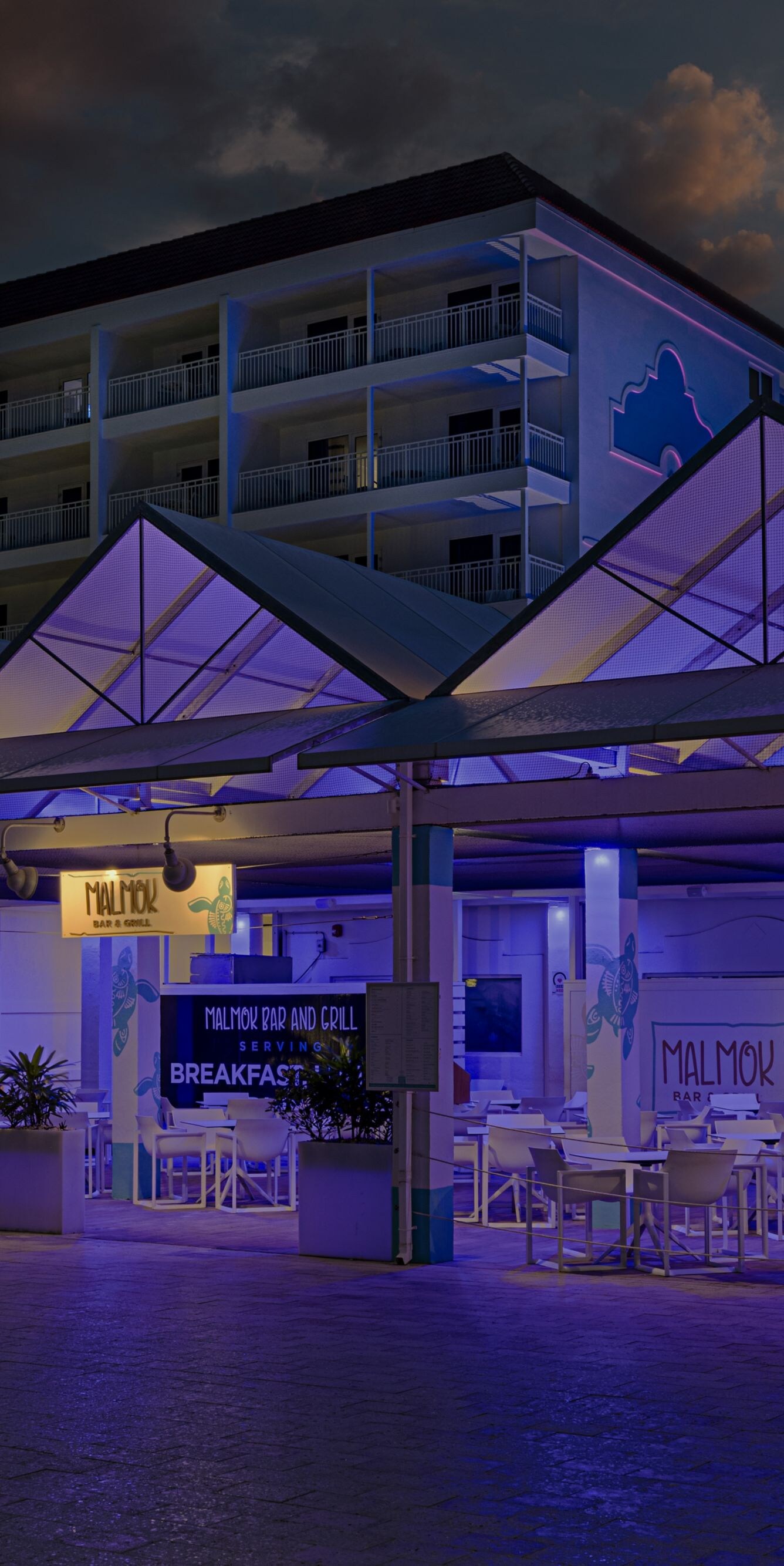 Een restaurantpaviljoen in de open lucht dat ’s avonds blauw verlicht is
