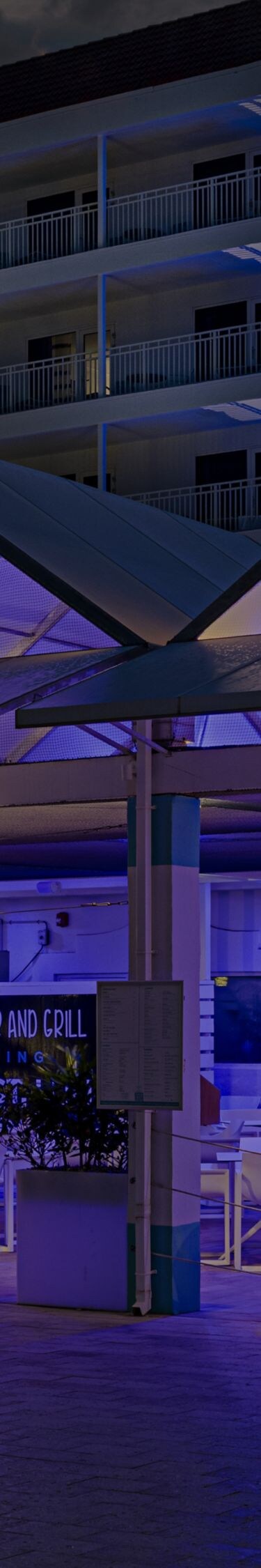 Een restaurantpaviljoen in de open lucht dat ’s avonds blauw verlicht is