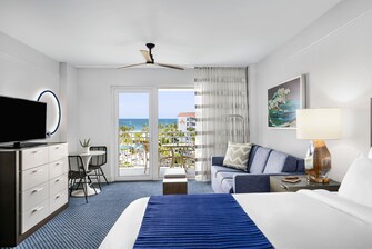 Ocean view guest room with bed, sofa and balcony