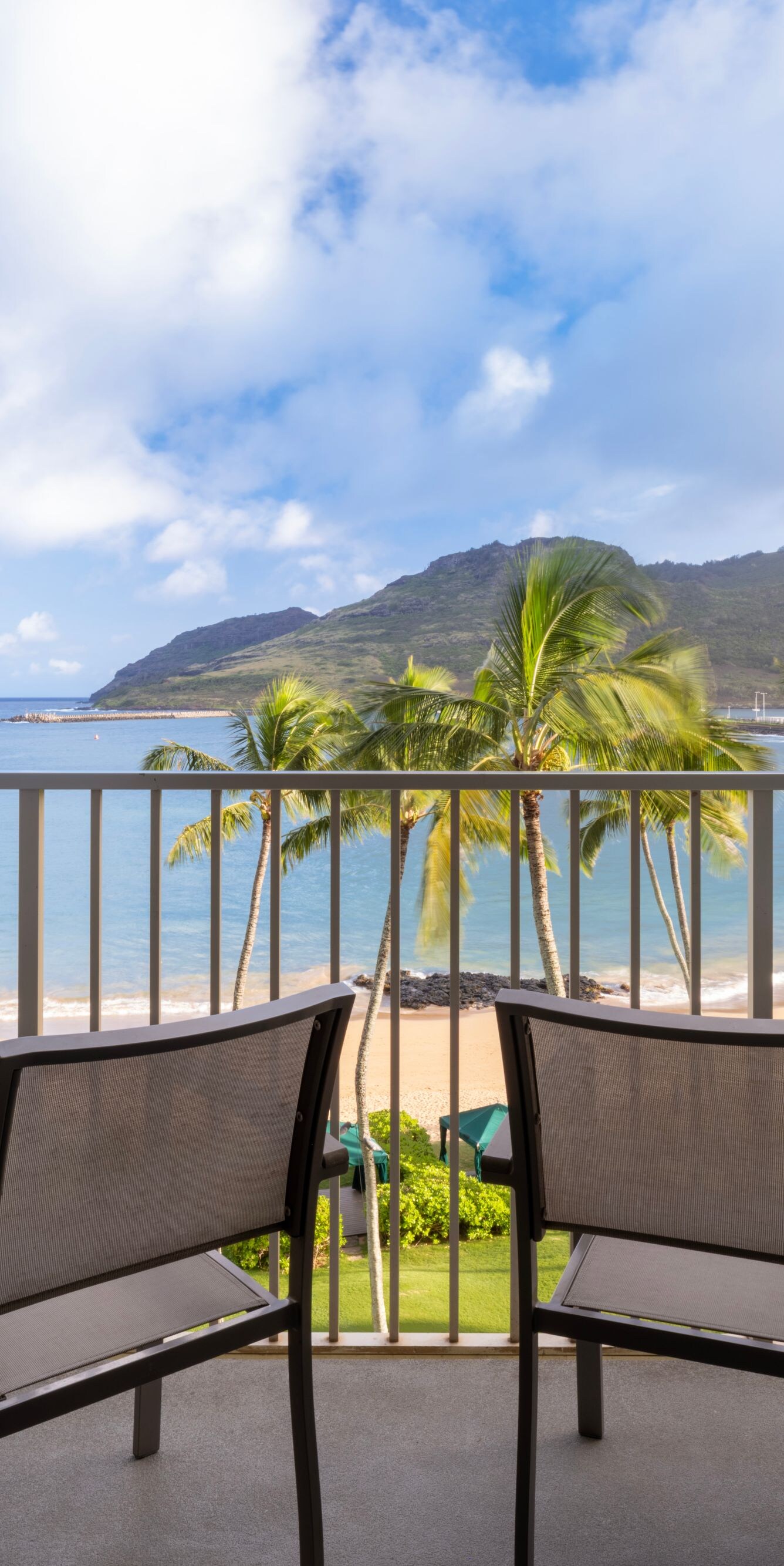 Balcony with tables, chairs and view of beach
