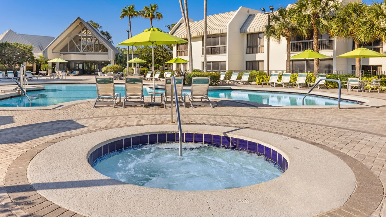 Whirlpool next to pool with chairs, umbrellas