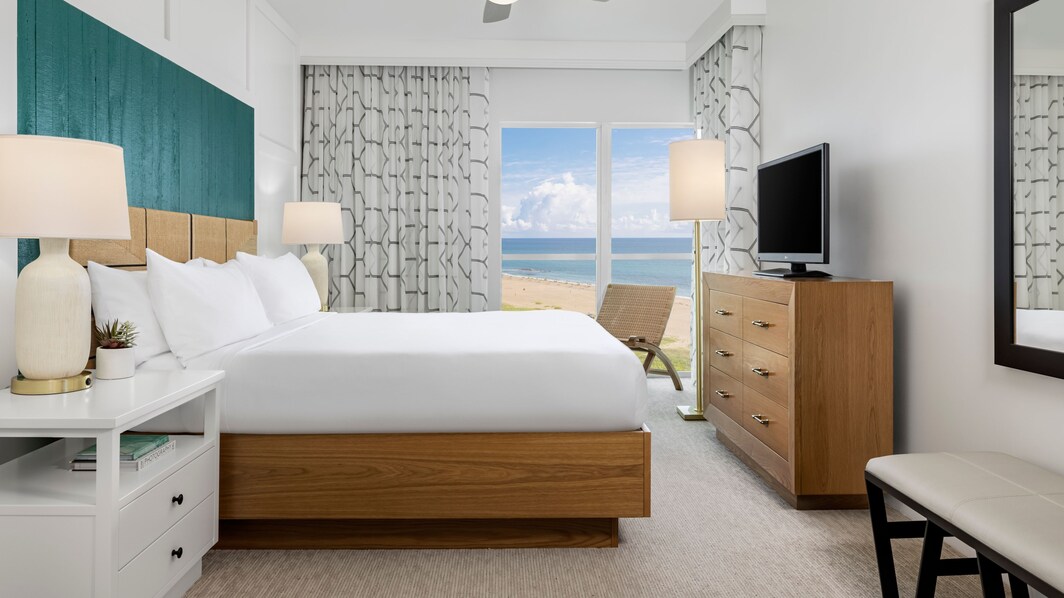 Quarto com cama king-size, vista para o mar e televisão