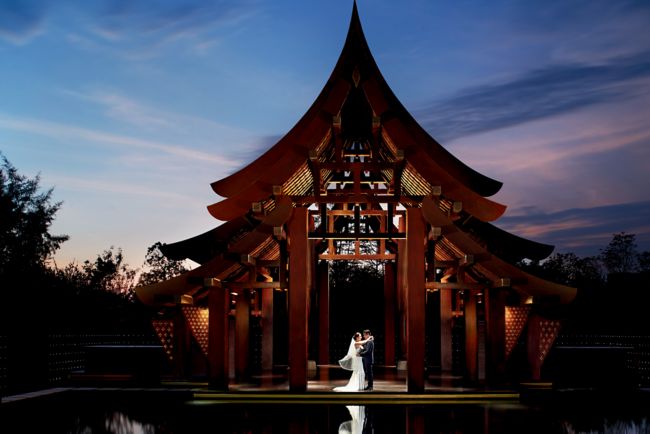 A bridal couple embraces at the Resort Pavilion while the water reflects a violet sunset