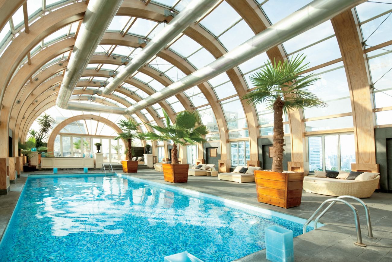 Indoor swimming pool under a curved glass roof