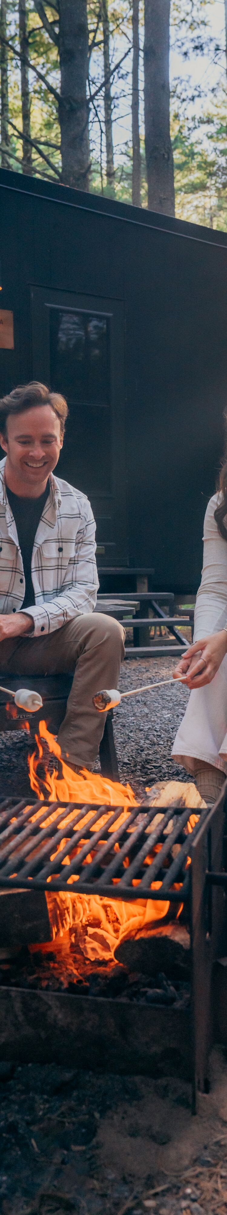 Couple roasting s'mores over fire pit