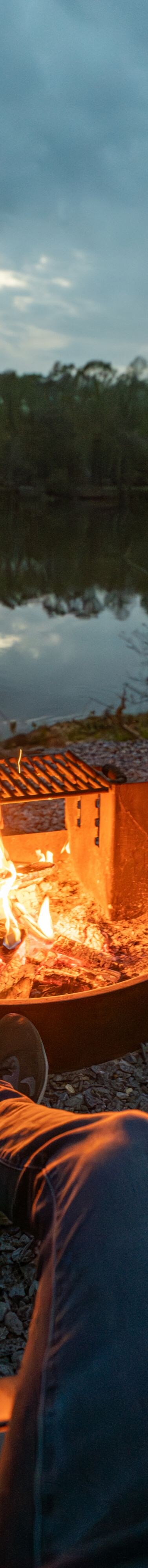person sitting fire pit next to a lake 