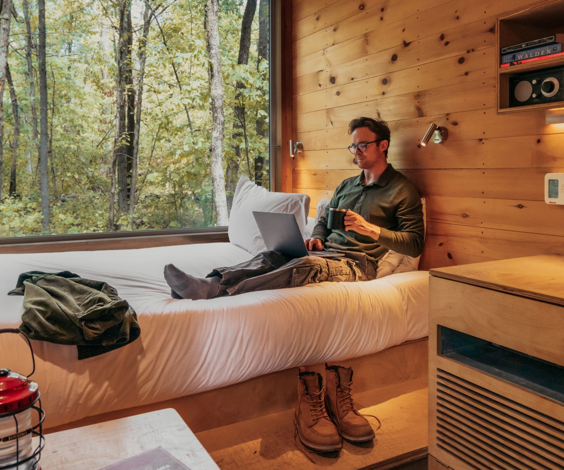 Man reading book in bed in front of window