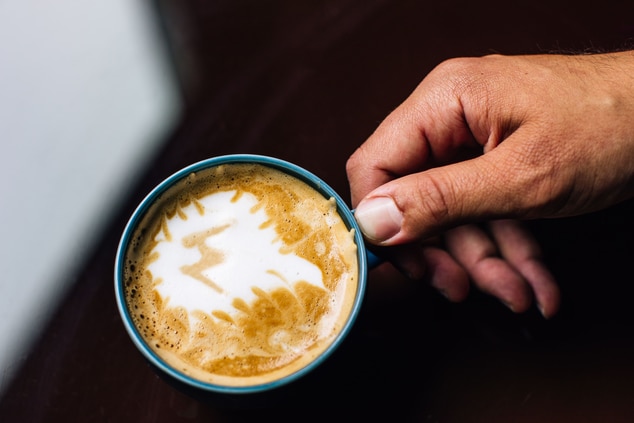 Hand holding coffee mug with artisanal coffee.