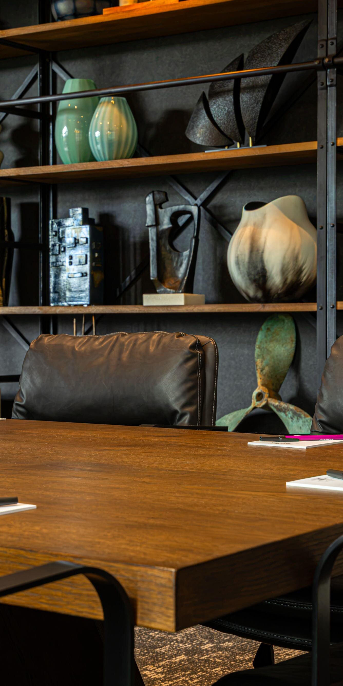 Boardroom table and wall of shelving with decor 