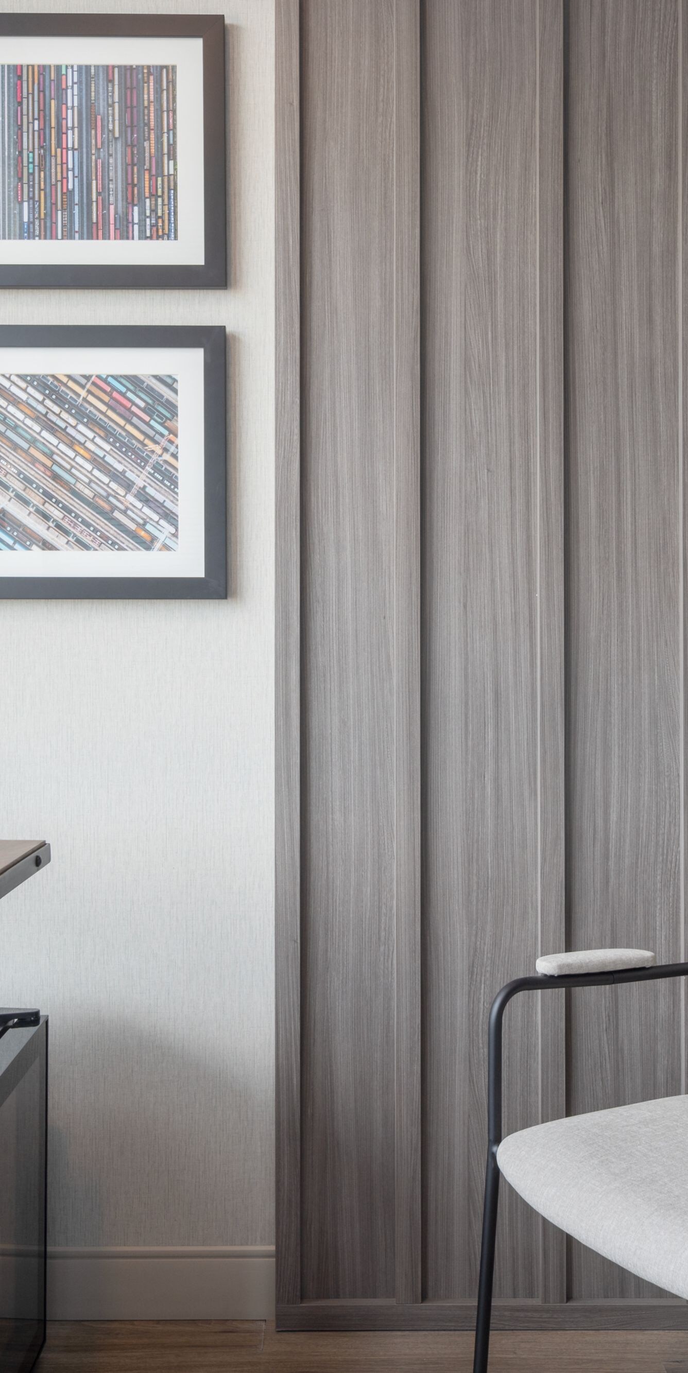 A desk and chair in front of a window and artwork.