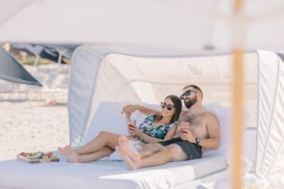 A couple laying on a beach cabana bed.