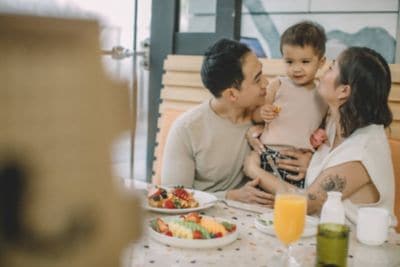 Asian family enjoying breakfast with young son.